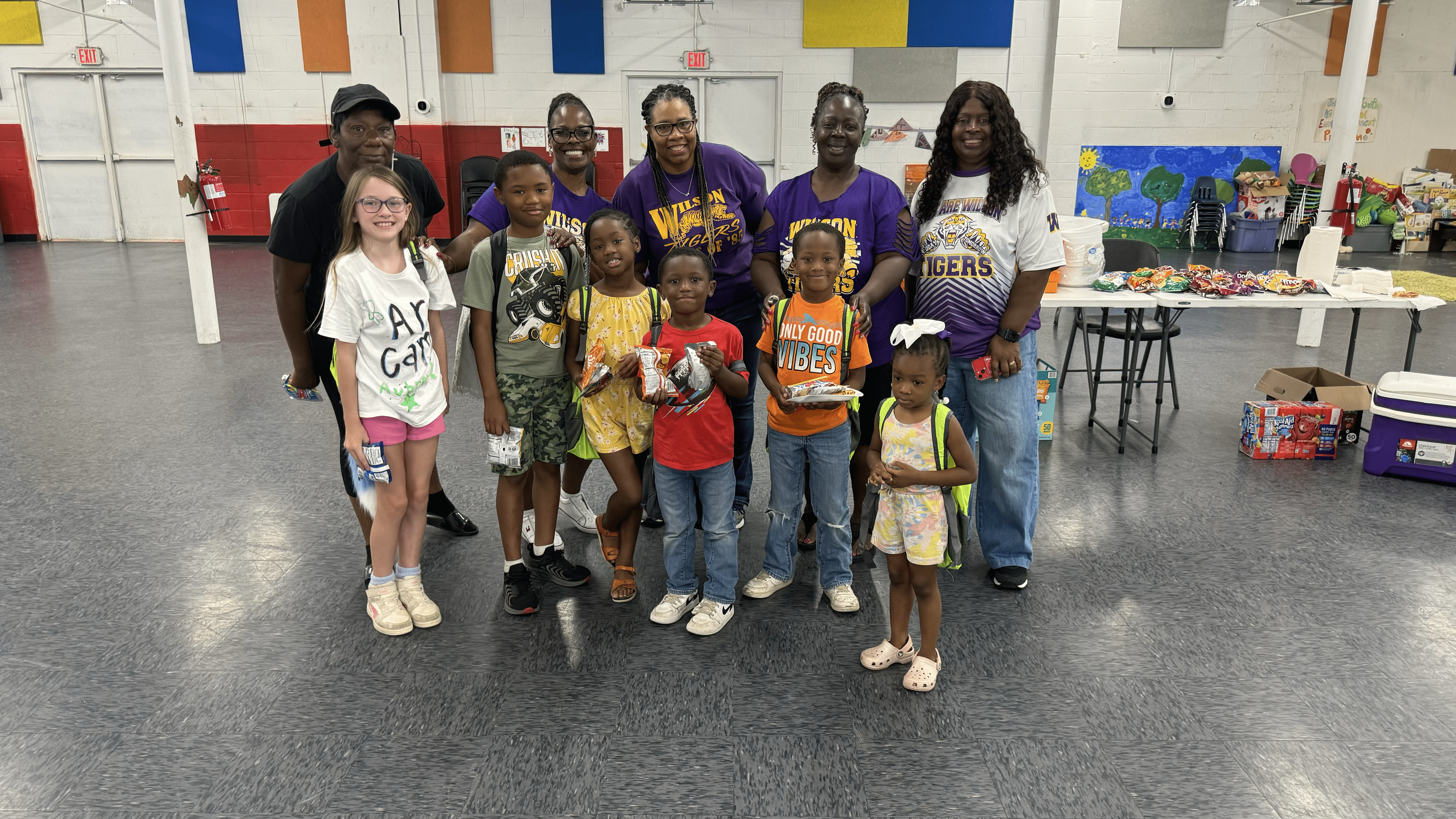 kids and adults gathered with backpacks and other new school supplies at community center event