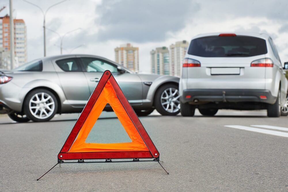 Traffic accident scene with a red warning triangle on the road.