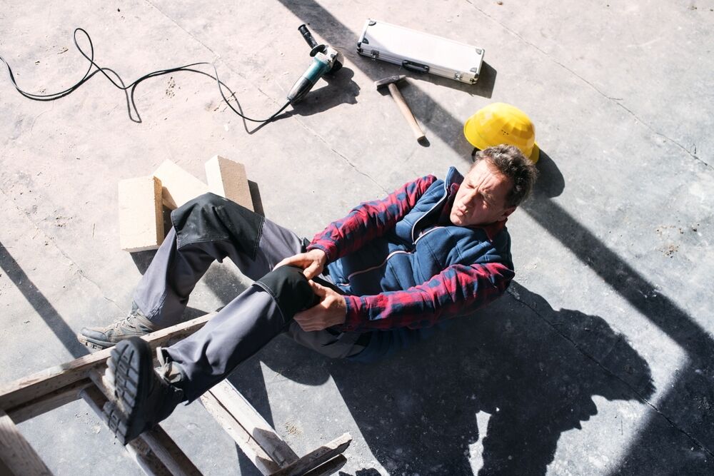 Male worker lying on the floor after falling from a ladder.