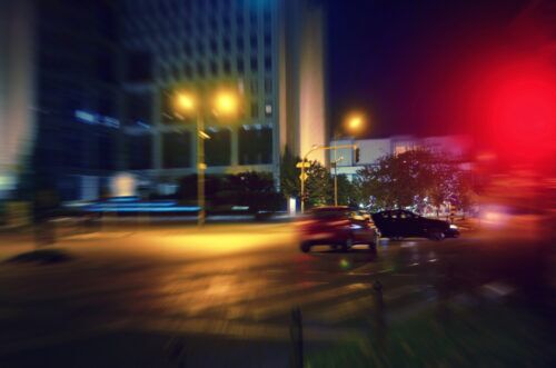 Blurry street view with a car hitting another one in an attempt to leave the scene
