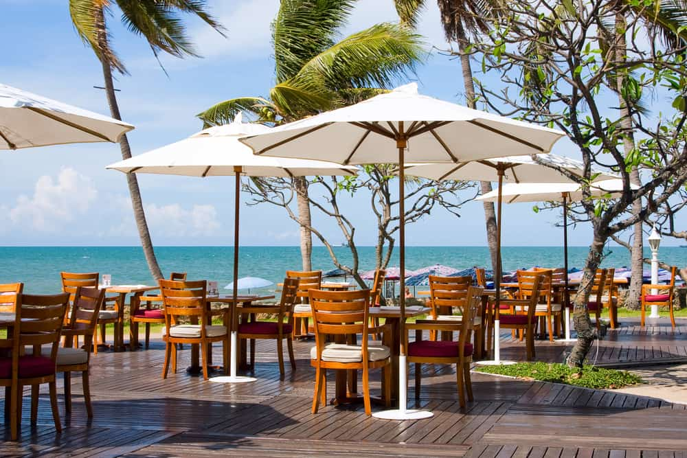 outdoor dining tables overlooking the ocean and palm trees