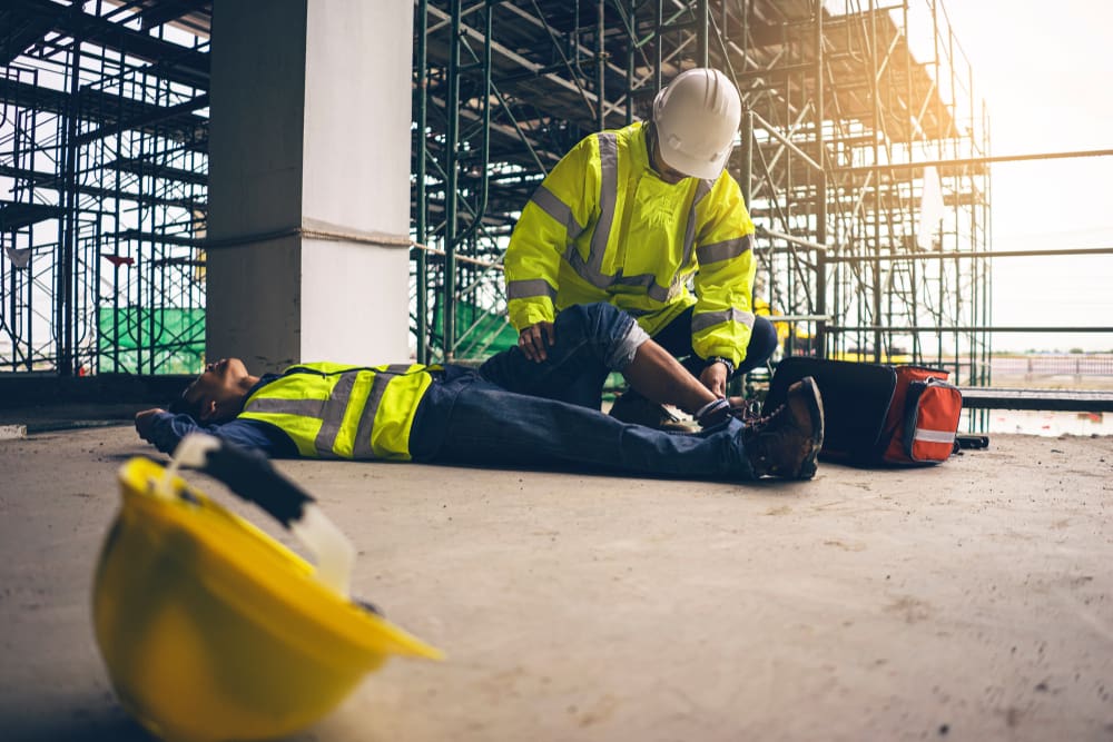 man administering medical care to coworker who fell from scaffold on construction site