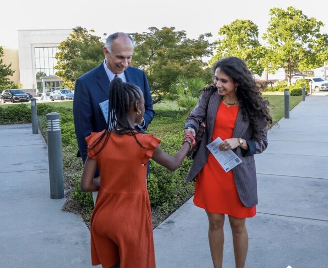 George and Kaylal being greeted by young member of Boys & Girls Club outside on a sidewalk ahead of Champions for Youth event