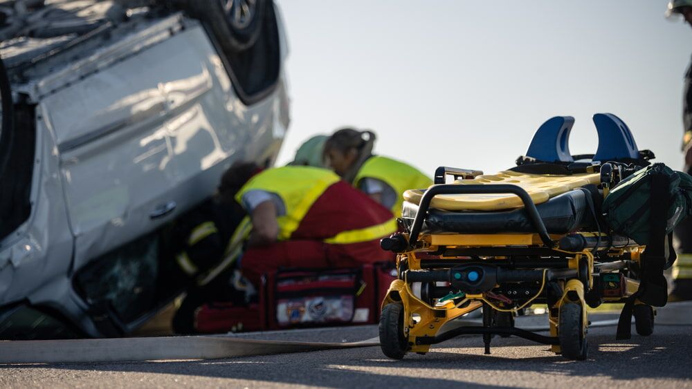 paramedics attempting to extract someone from an overturned vehicle after an accident with stretcher in the foreground