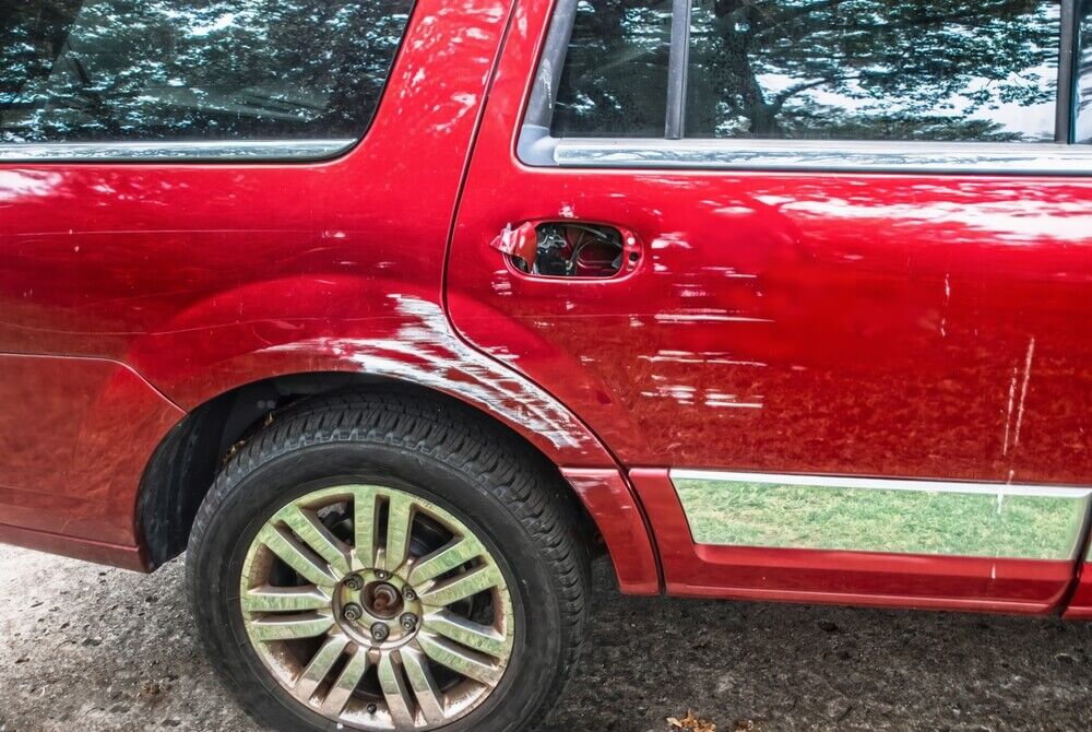 Bright cherry red pickup truck that's been sideswiped by white vehicle - right front door handle missing