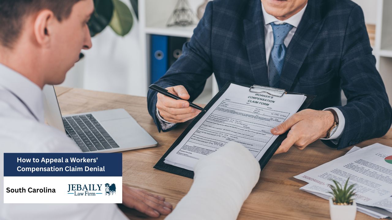 A suited man reviews a worker's compensation claim with an injured client at a wooden desk, pointing at the form with a pen in a serious, professional setting.