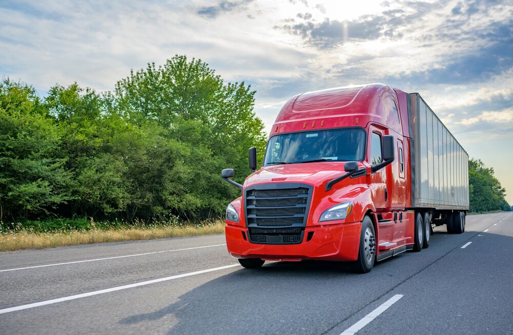 red semi truck driving down the highway