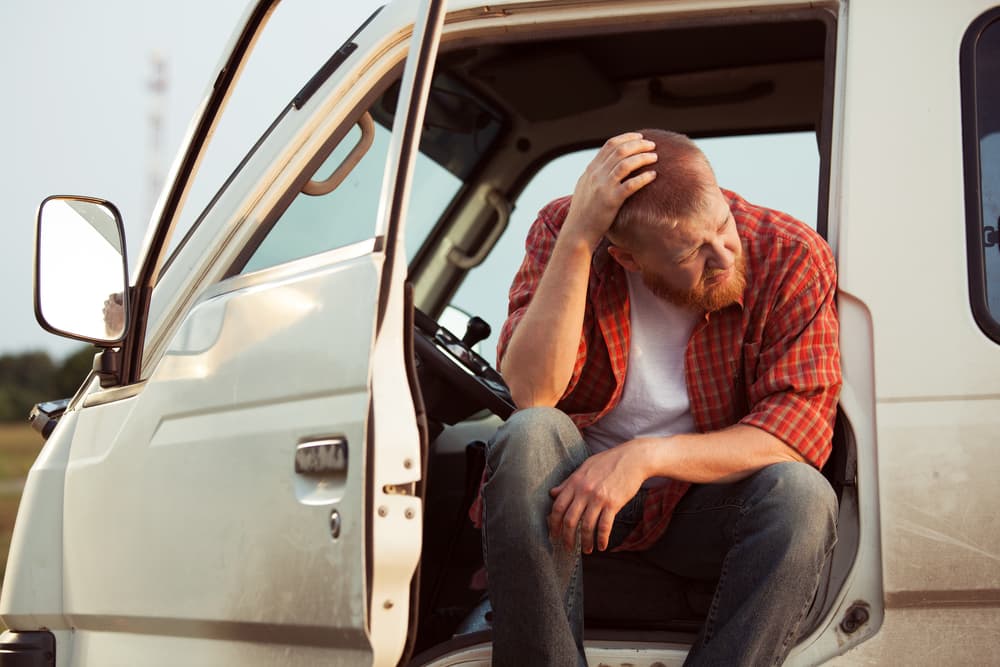 man in broken down car waiting for help on hot day