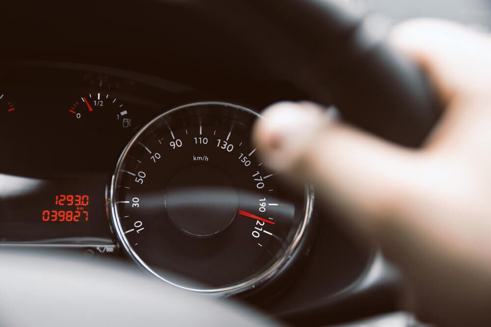 Man holds steering wheel and speedometer show high speed